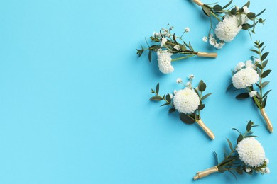 Many stylish boutonnieres on light blue background, flat lay. Space for text