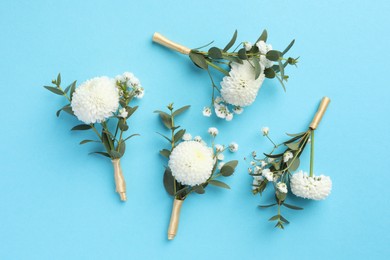 Many stylish boutonnieres on light blue background, flat lay