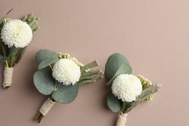 Photo of Small stylish boutonnieres on beige background, flat lay. Space for text