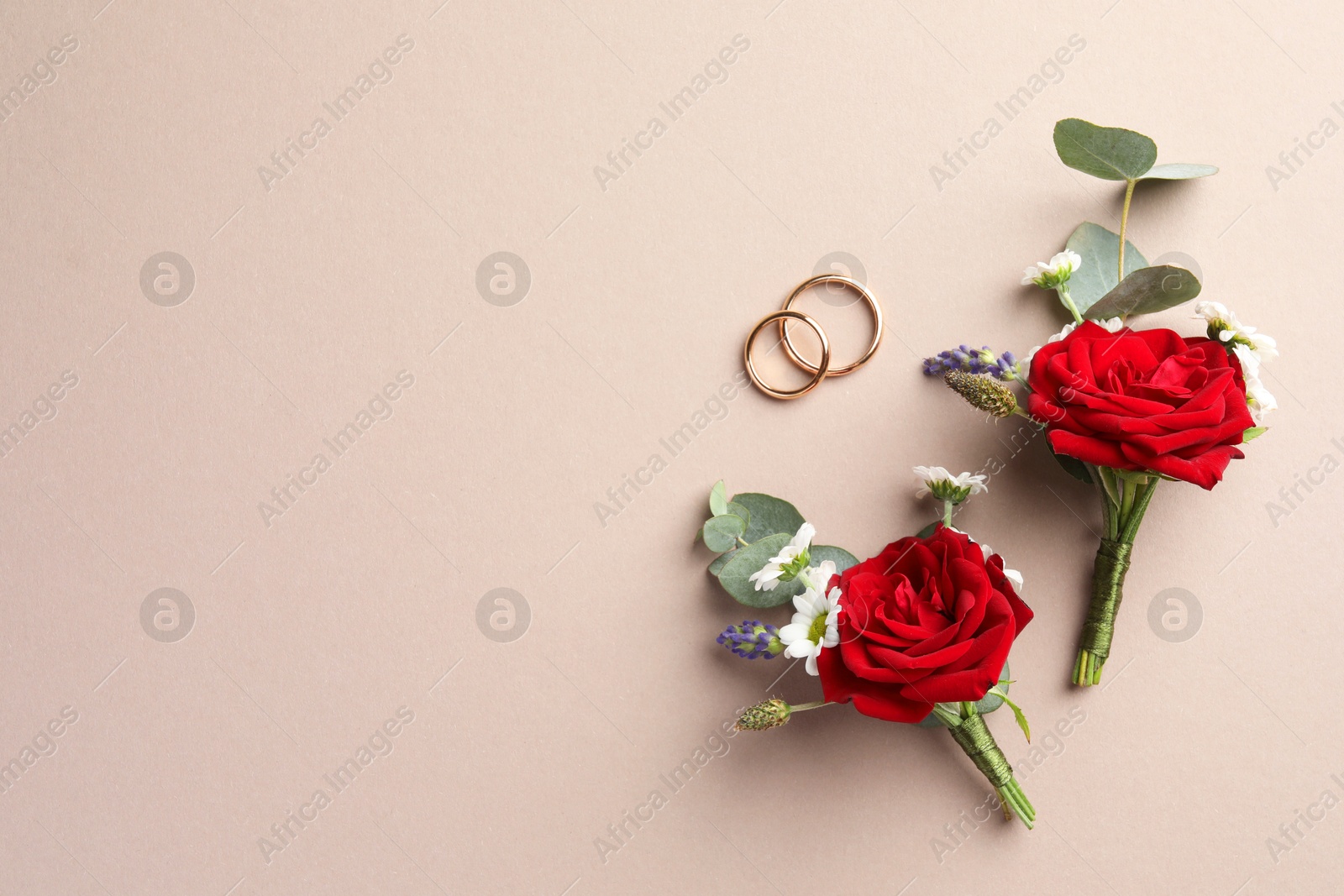 Photo of Small stylish boutonnieres and rings on beige background, flat lay. Space for text