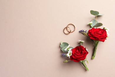 Small stylish boutonnieres and rings on beige background, flat lay. Space for text