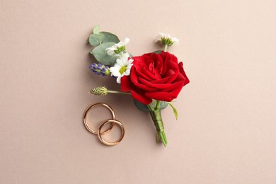 Photo of Small stylish boutonniere and rings on beige background, top view