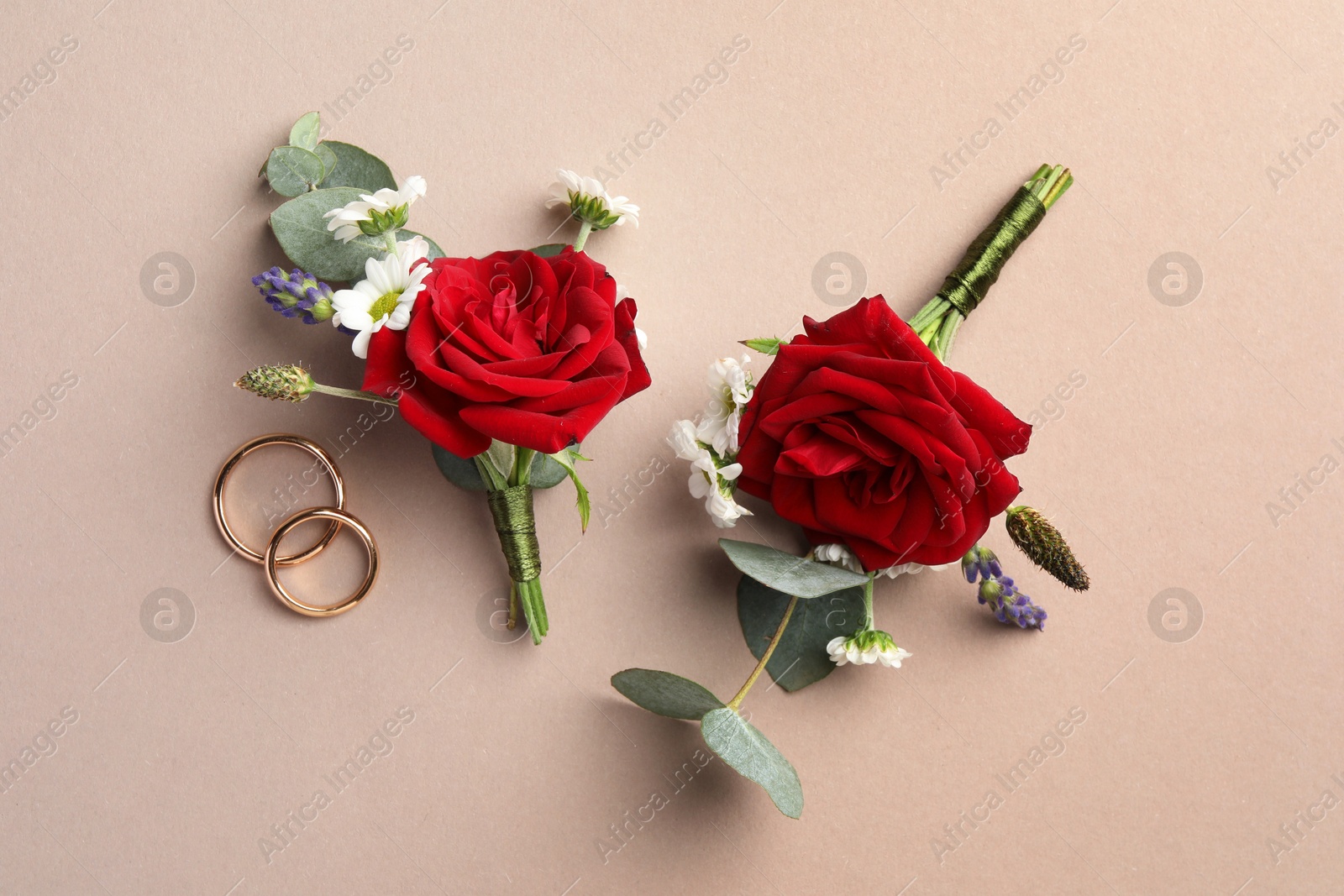 Photo of Small stylish boutonnieres and rings on beige background, flat lay