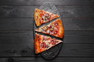 Photo of Board with pieces of delicious pizza Diablo on black wooden table, top view