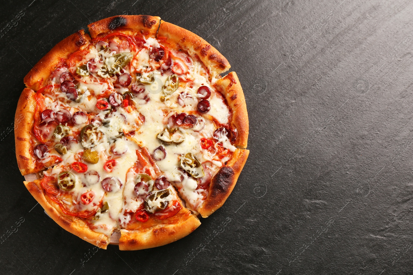 Photo of Delicious pizza Diablo on dark textured table, top view. Space for text