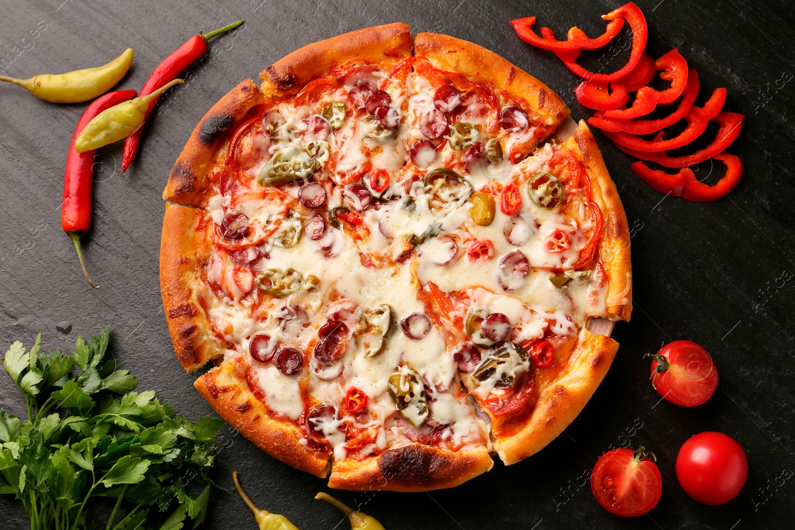 Photo of Delicious pizza Diablo among products on dark textured table, flat lay