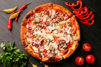 Photo of Delicious pizza Diablo among products on dark textured table, flat lay