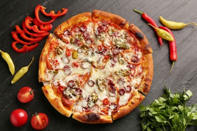 Photo of Delicious pizza Diablo among products on dark textured table, flat lay