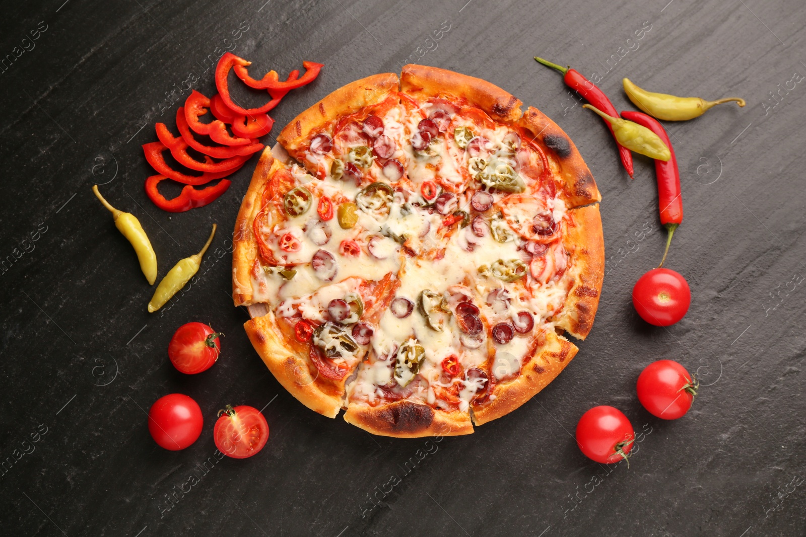 Photo of Delicious pizza Diablo among products on dark textured table, flat lay