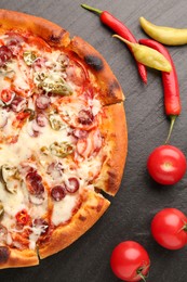 Photo of Delicious pizza Diablo, tomatoes and peppers on dark textured table, flat lay