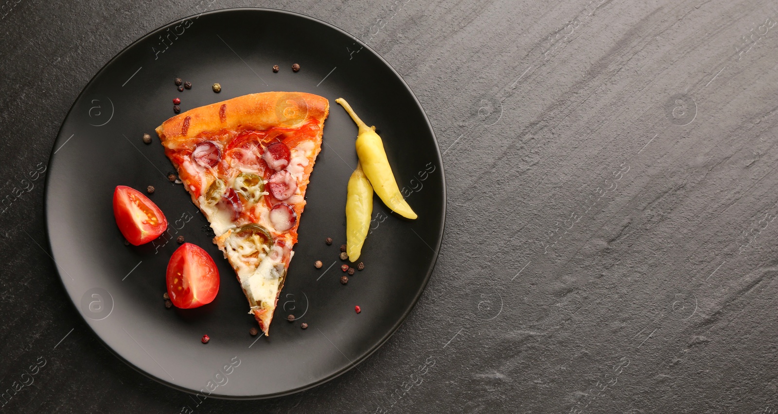 Photo of Plate with delicious pizza Diablo, pepper, tomato and peppercorns on dark textured table, top view. Space for text