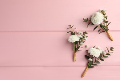 Many small stylish boutonnieres on pink wooden table, flat lay. Space for text