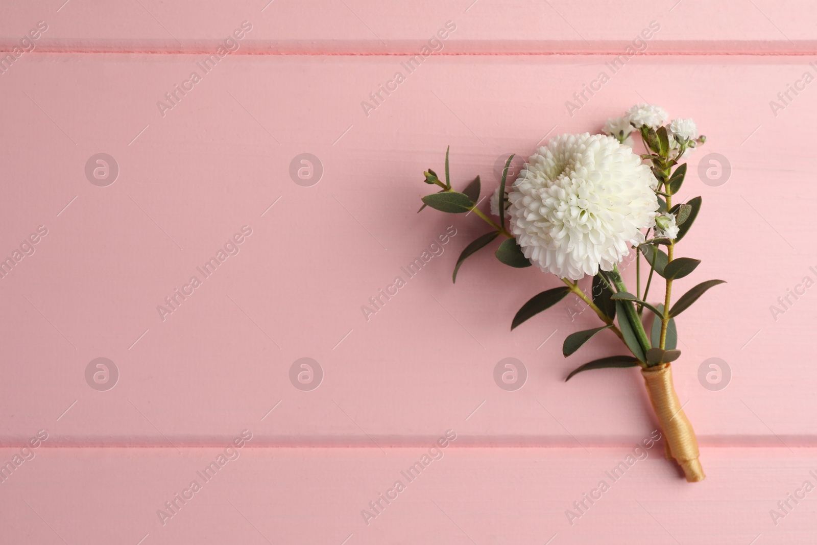 Photo of Small stylish boutonniere on pink wooden table, top view. Space for text