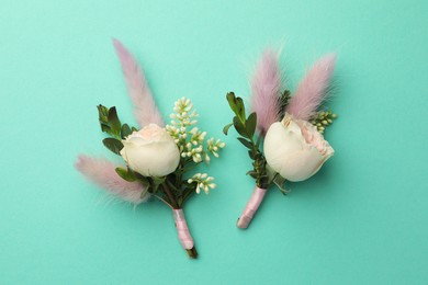 Small stylish boutonnieres on turquoise background, flat lay