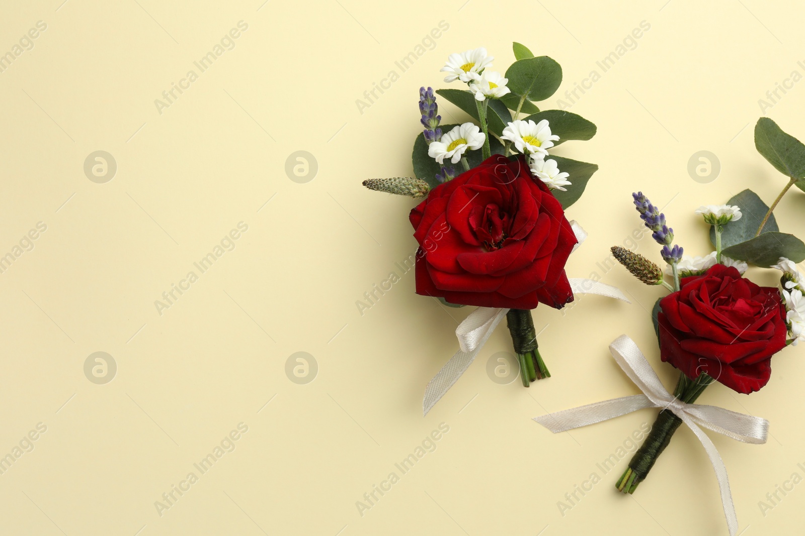 Photo of Stylish red boutonnieres on beige background, flat lay. Space for text