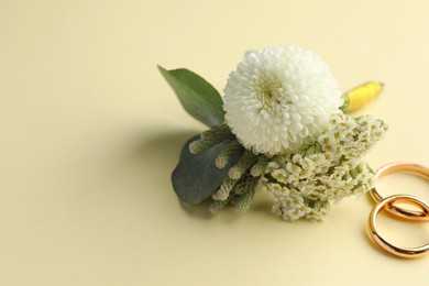 Small stylish boutonniere and rings on beige background. Space for text