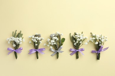 Photo of Many stylish boutonnieres on beige background, flat lay. Space for text