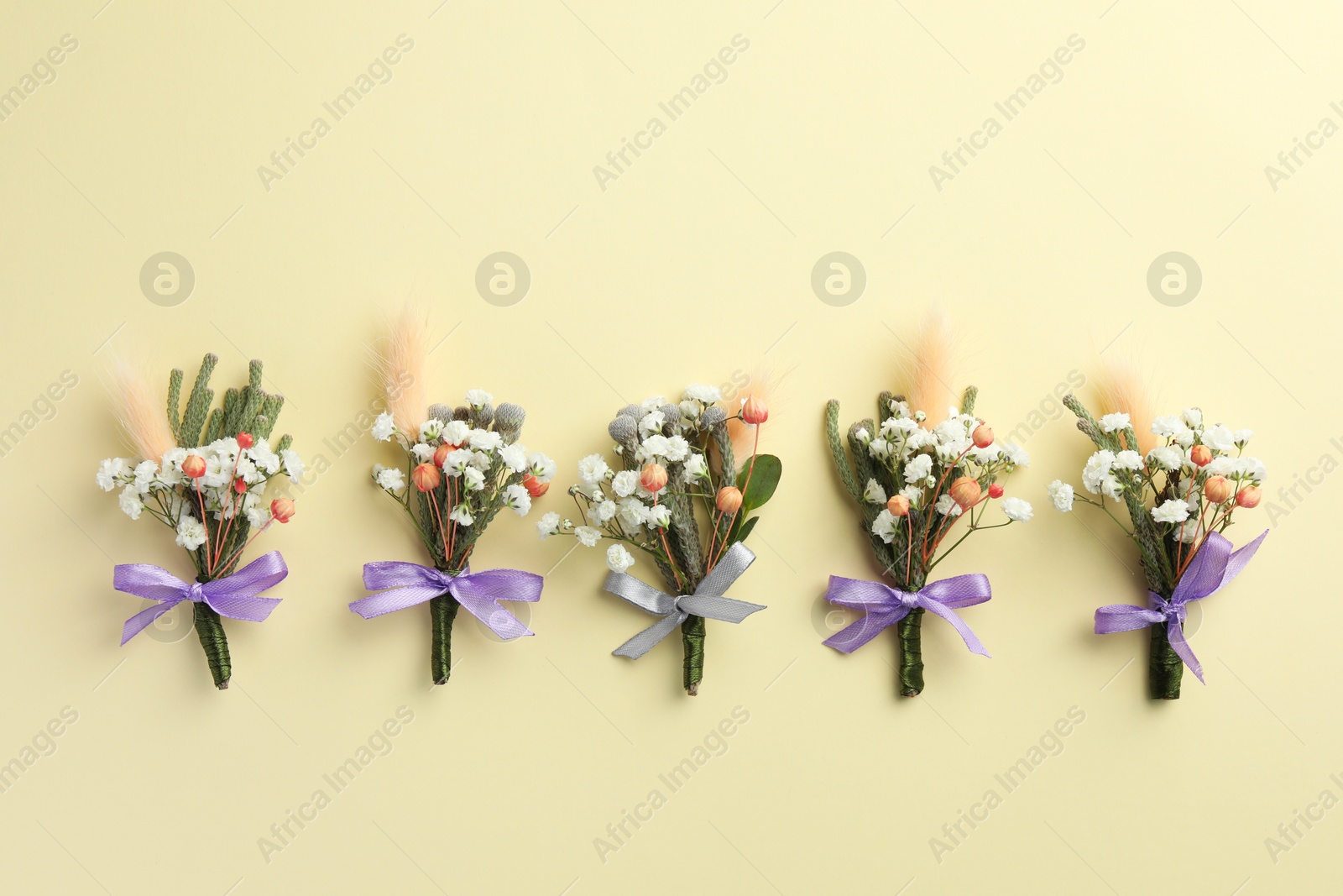 Photo of Many stylish boutonnieres on beige background, flat lay. Space for text