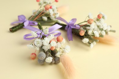 Many stylish boutonnieres on beige background, closeup