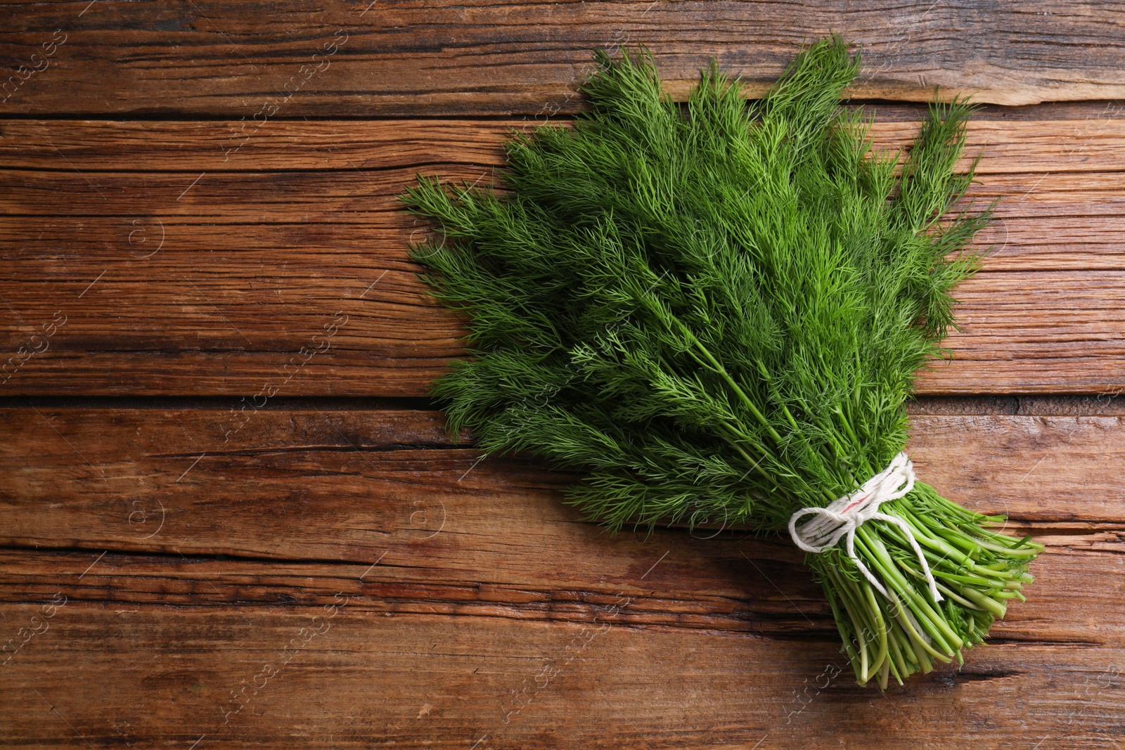 Photo of Bunch of fresh green dill on wooden table, top view. Space for text