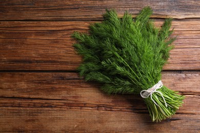 Photo of Bunch of fresh green dill on wooden table, top view. Space for text