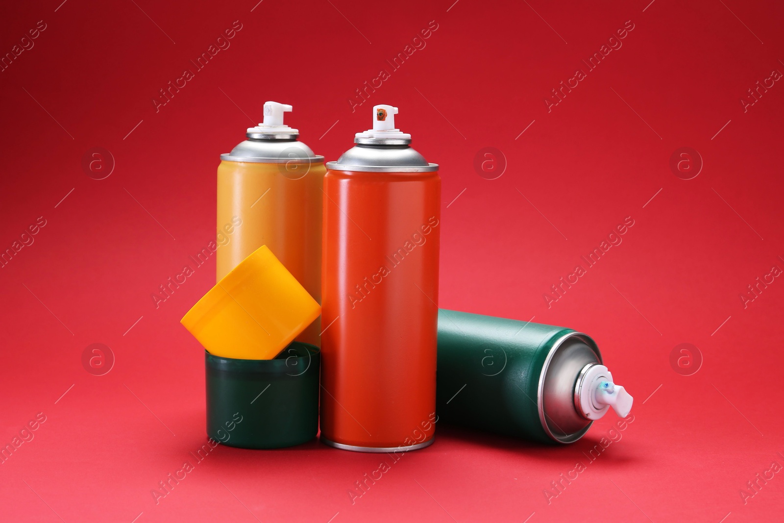 Photo of Many spray paint cans on red background