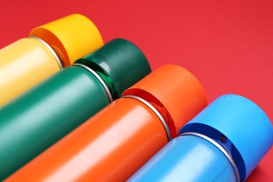 Photo of Many spray paint cans on red background, closeup