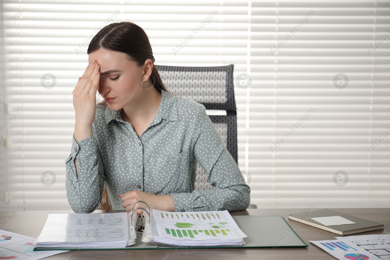 Photo of Embarrassed woman at wooden table with documents in office, space for text