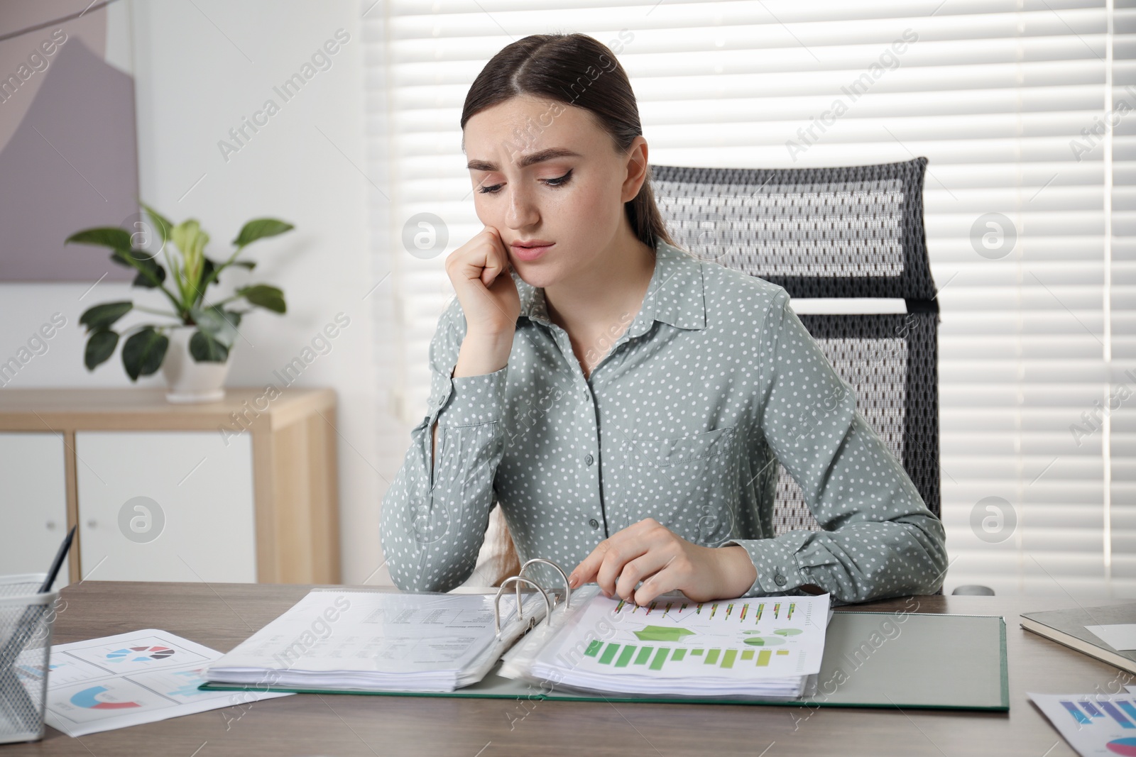 Photo of Embarrassed woman at wooden table with documents in office