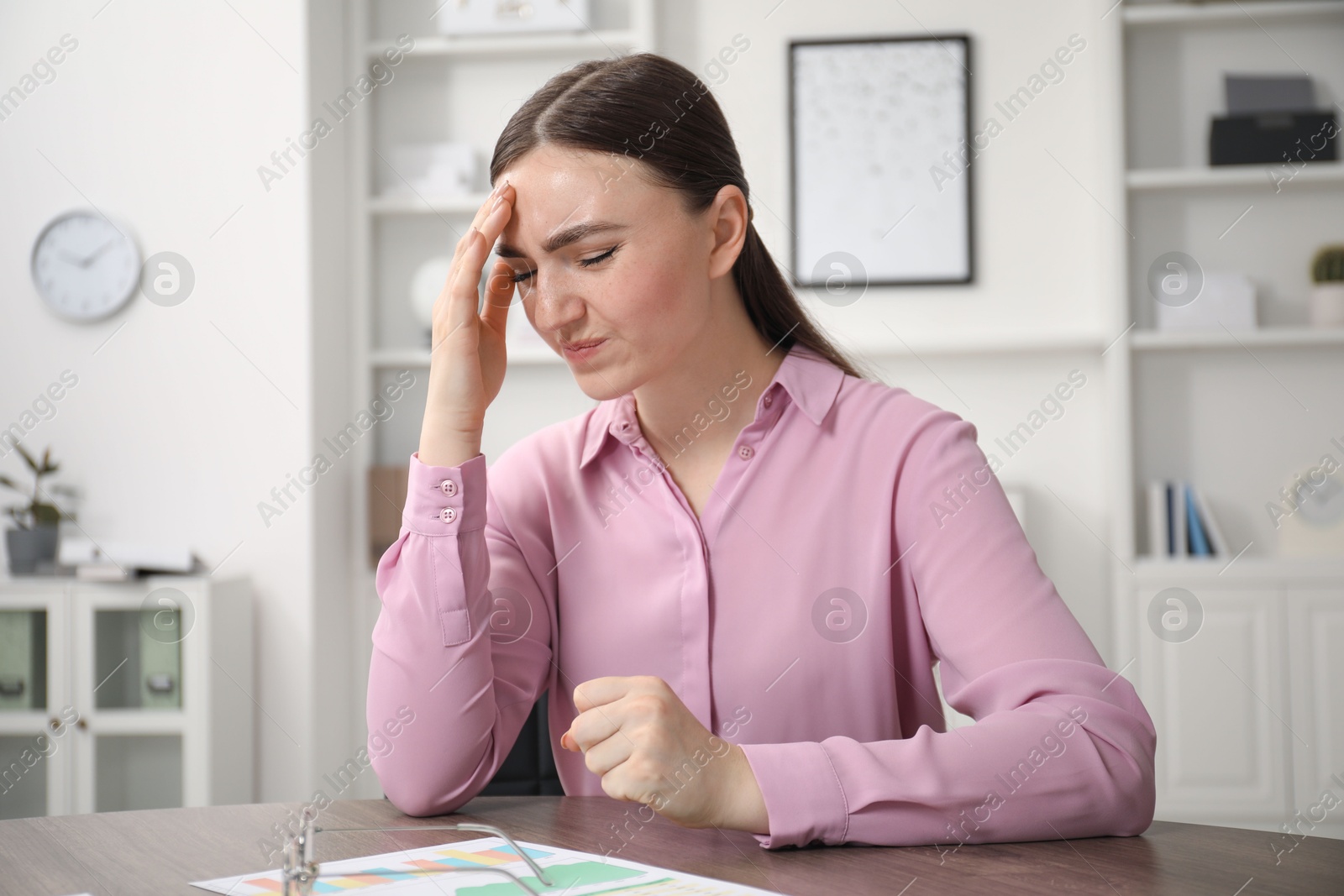 Photo of Embarrassed woman at wooden table in office