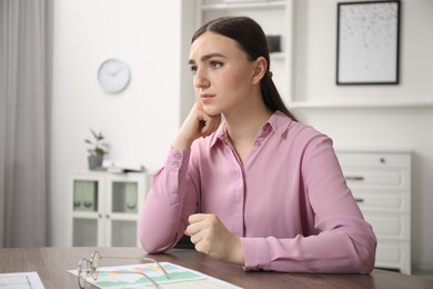 Photo of Embarrassed woman at wooden table in office
