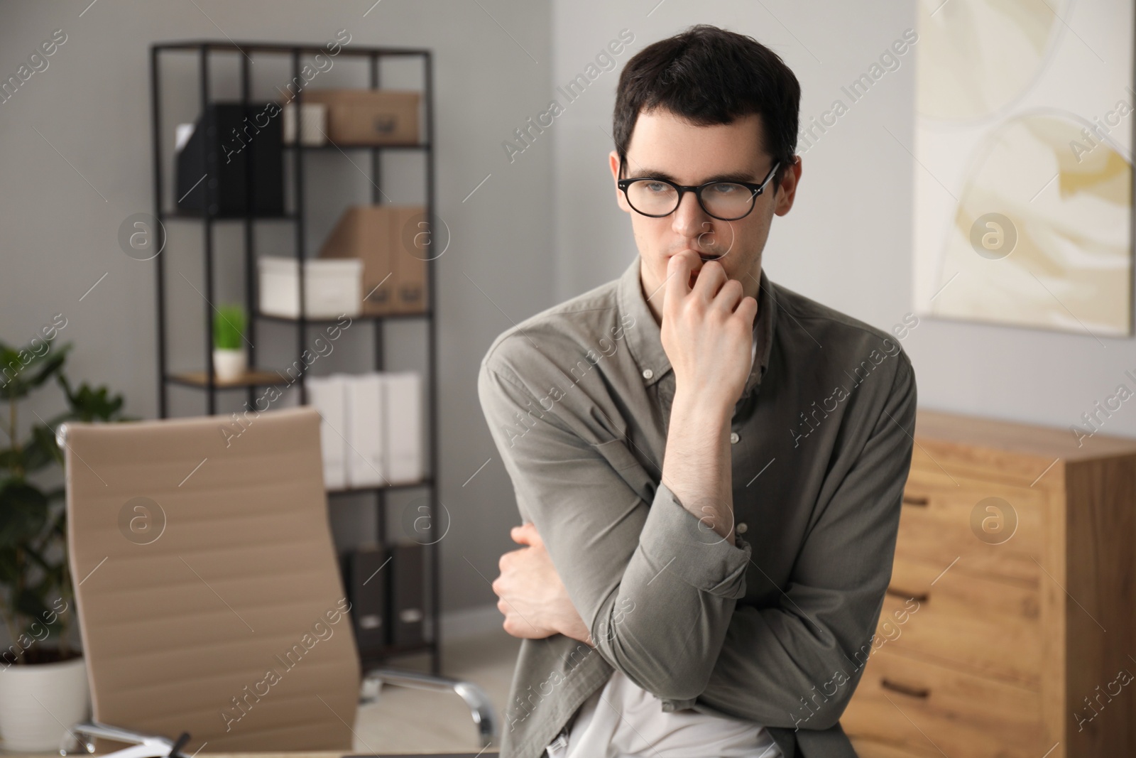 Photo of Embarrassed young man in glasses in office