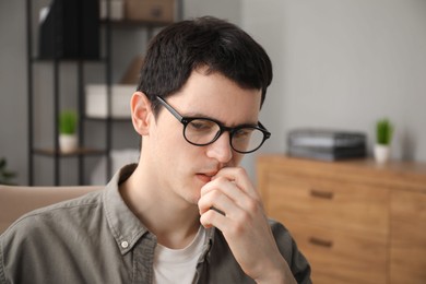 Photo of Embarrassed young man in glasses in office, space for text