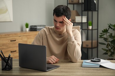 Photo of Embarrassed man at wooden table with laptop in office