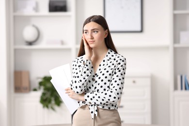 Photo of Embarrassed young woman with documents in office