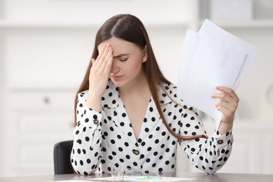 Photo of Embarrassed woman with documents at table in office