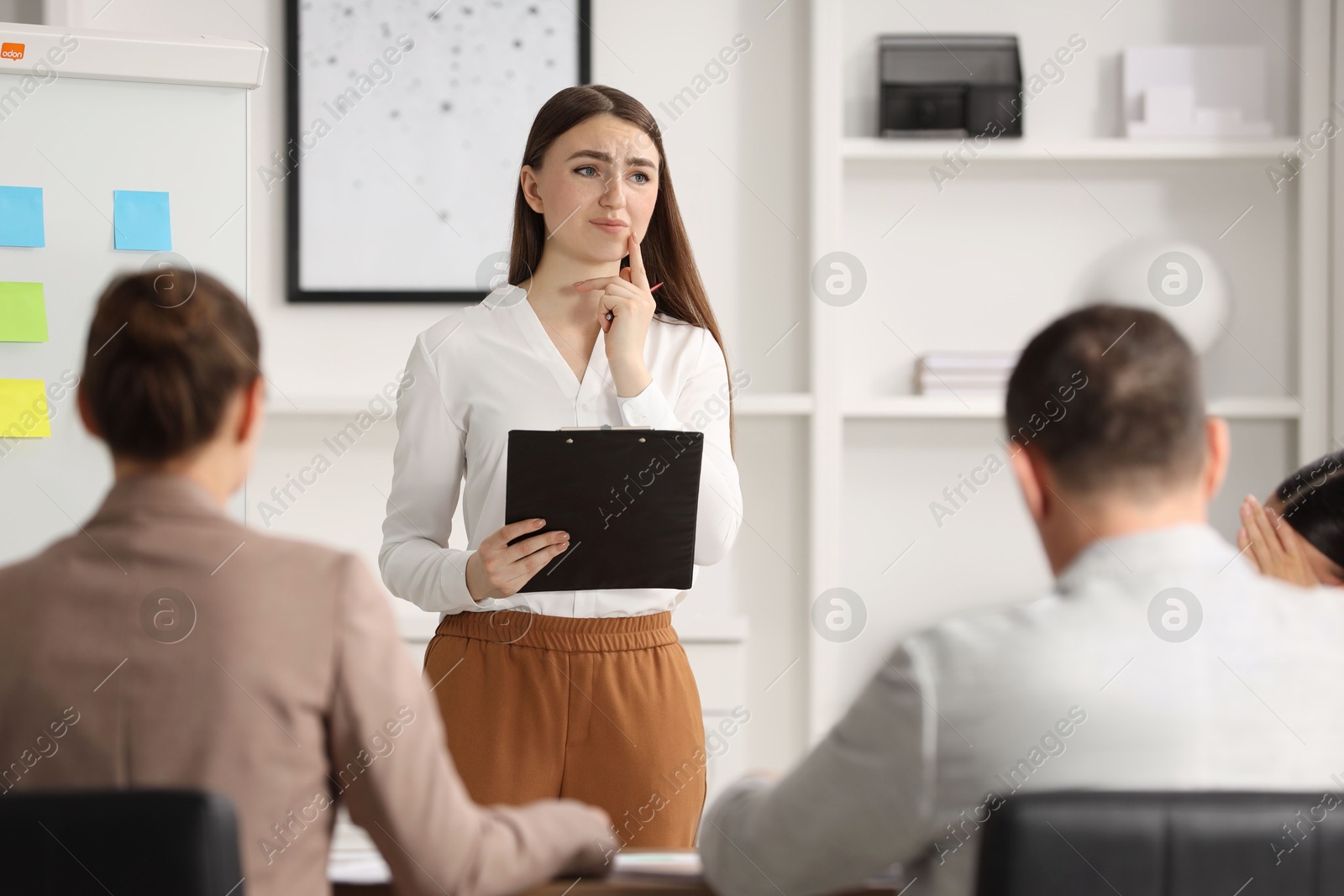 Photo of Woman with clipboard feeling embarrassed during business meeting in office