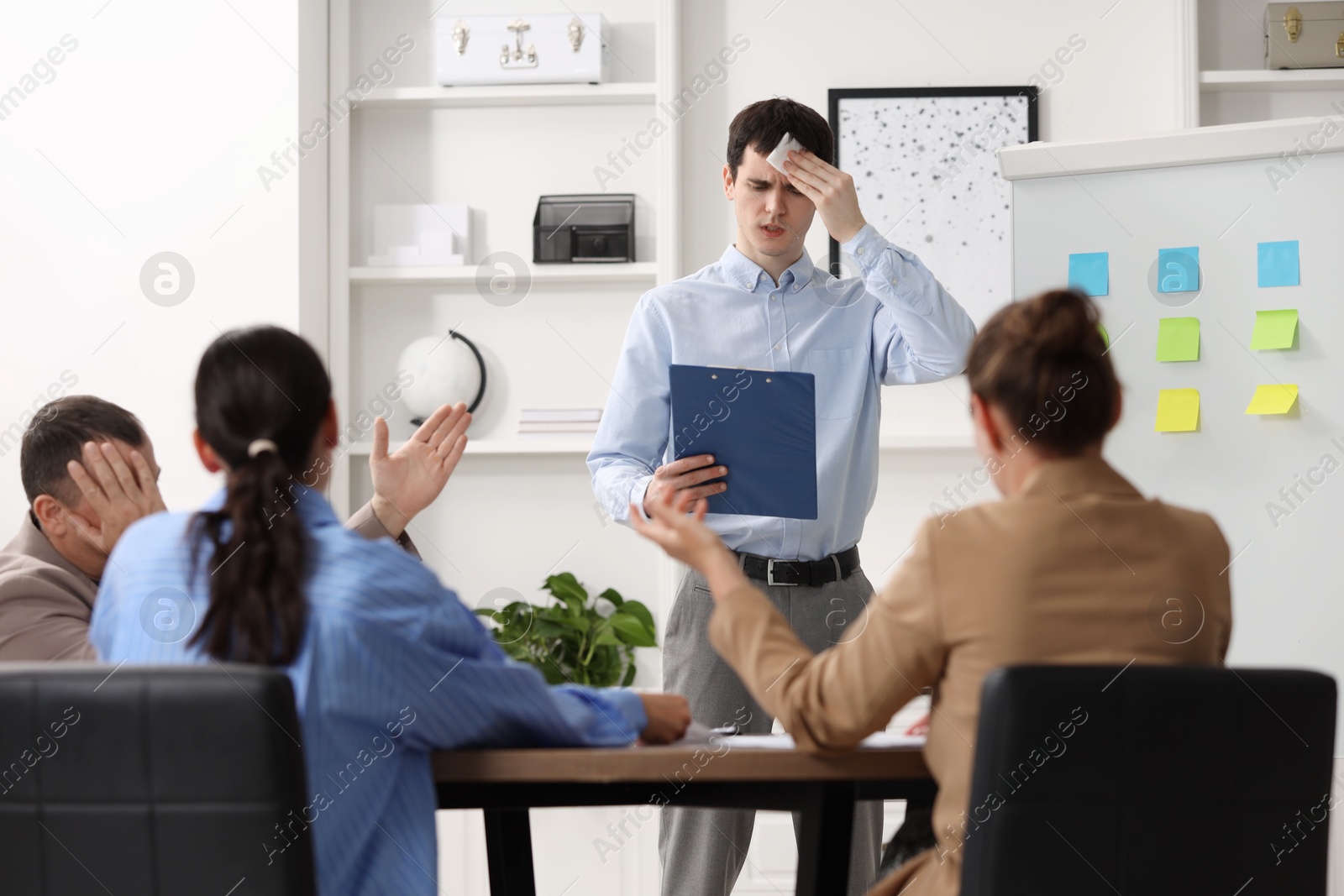 Photo of Man with clipboard feeling embarrassed during business meeting in office