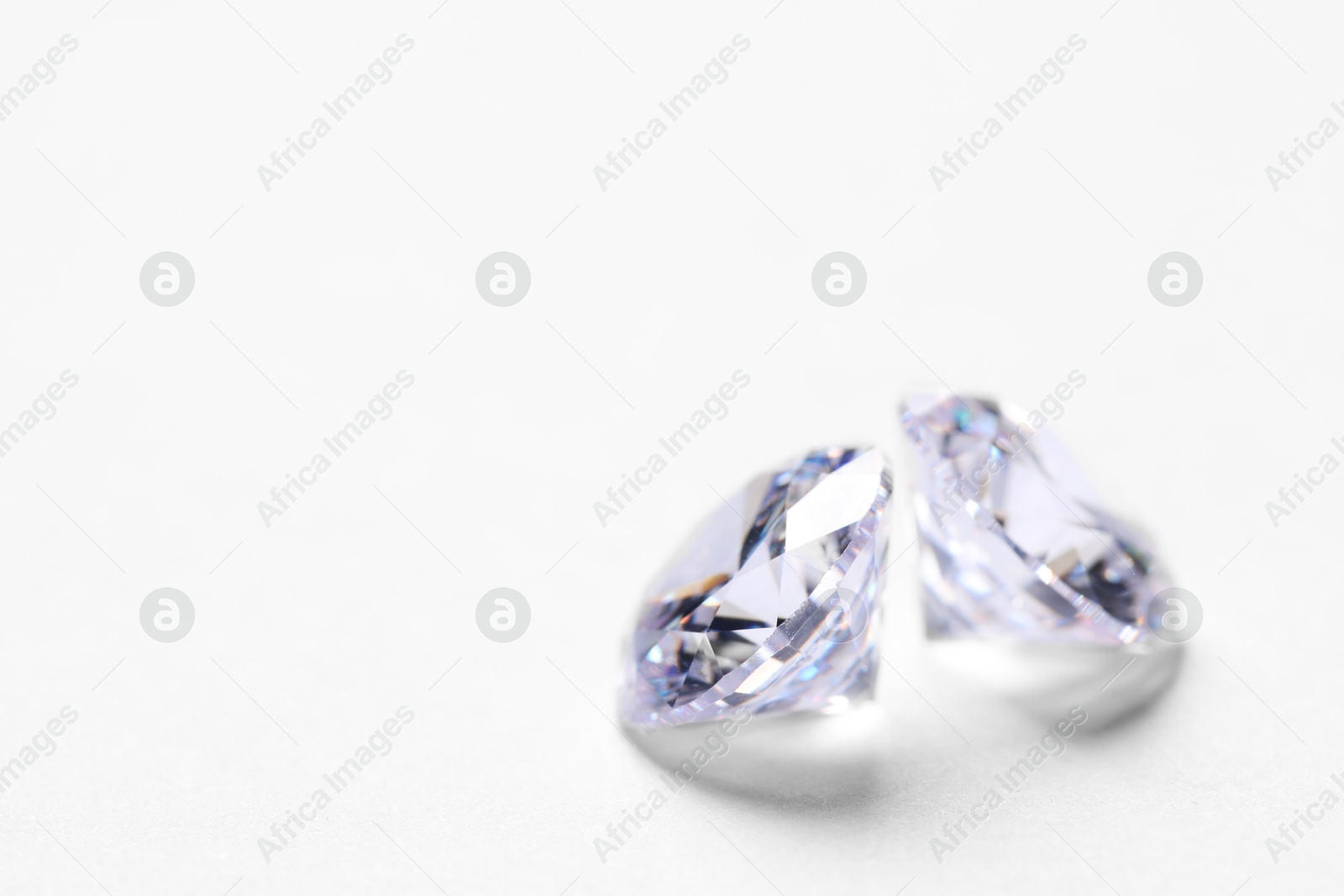 Photo of Two beautiful shiny diamonds on white background, closeup. Space for text