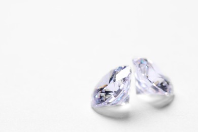 Photo of Two beautiful shiny diamonds on white background, closeup. Space for text