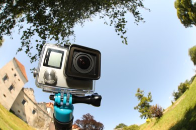 Modern action camera with monopod outdoors. Fisheye lens effect