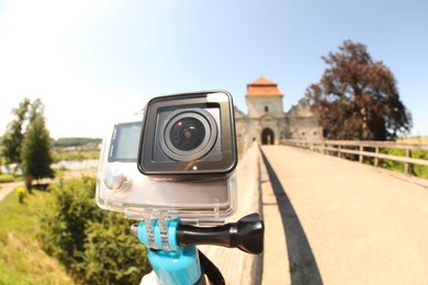 Modern action camera with monopod outdoors, closeup. Fisheye lens effect