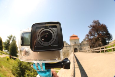 Modern action camera and monopod outdoors, closeup. Fisheye lens effect