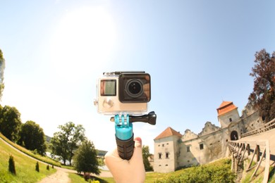 Photo of Man with modern action camera and monopod outdoors, closeup. Fisheye lens effect