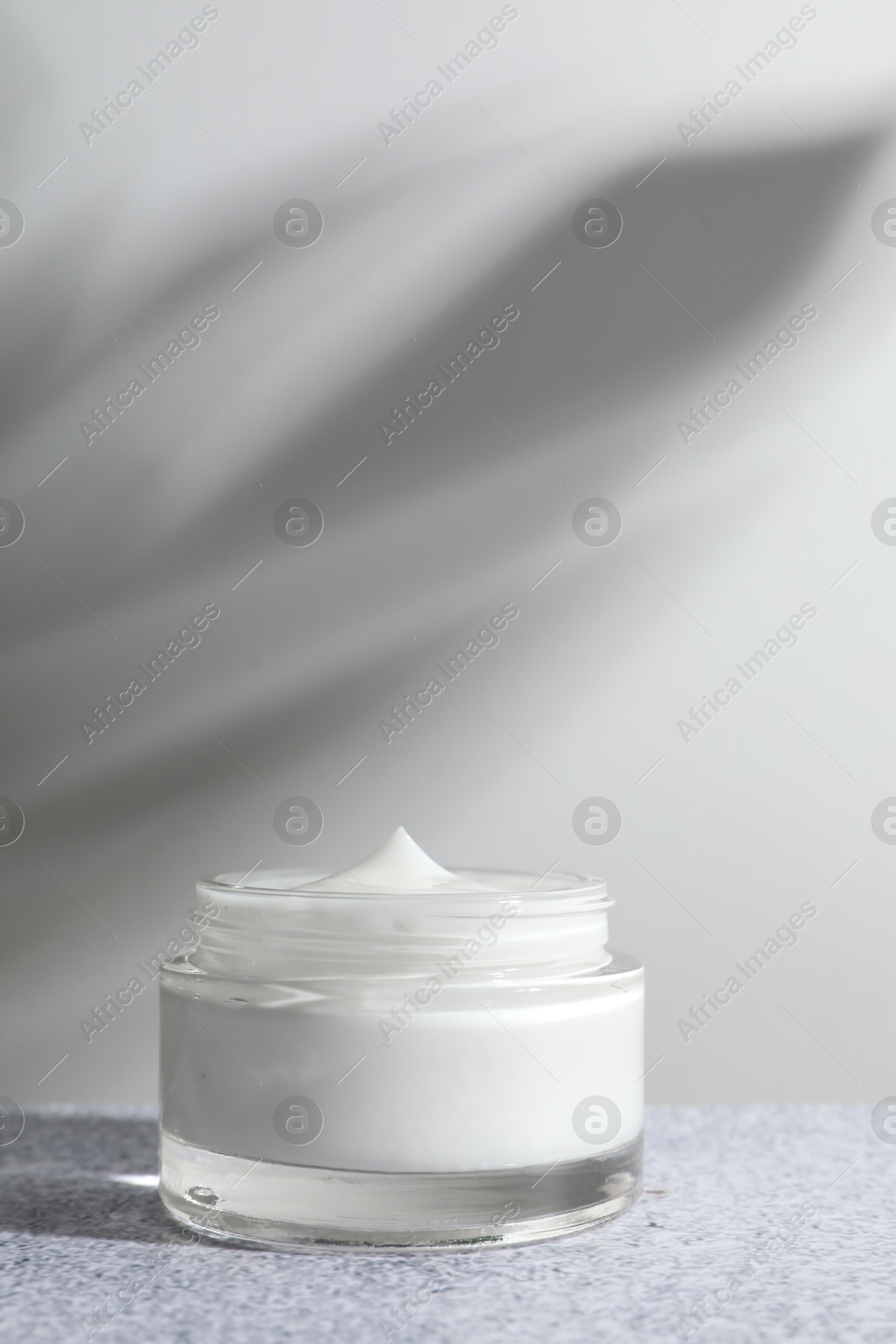 Photo of Face cream in jar on grey textured table. Cosmetic product