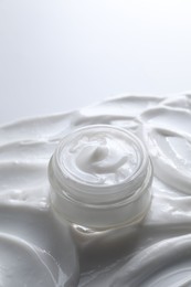 Photo of Face cream in jar on cosmetic product, closeup