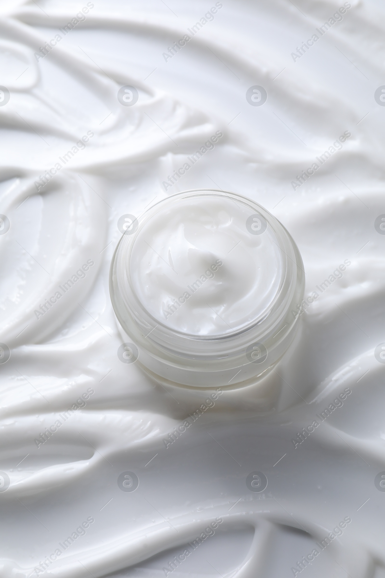 Photo of Face cream in jar on cosmetic product, above view