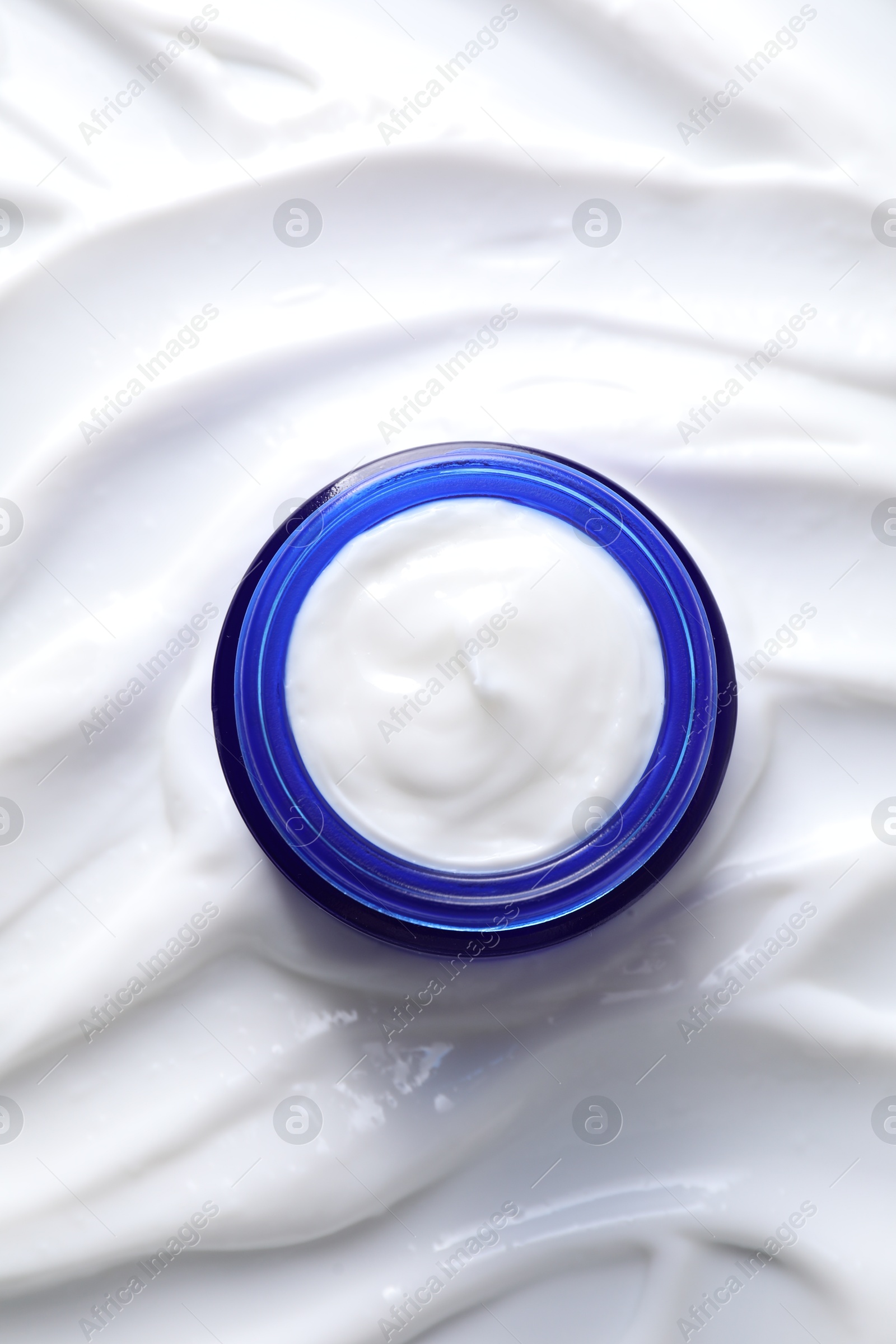 Photo of Face cream in jar on cosmetic product, top view