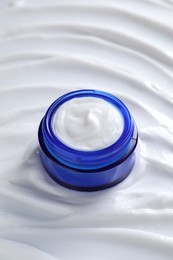 Photo of Face cream in jar on cosmetic product, closeup