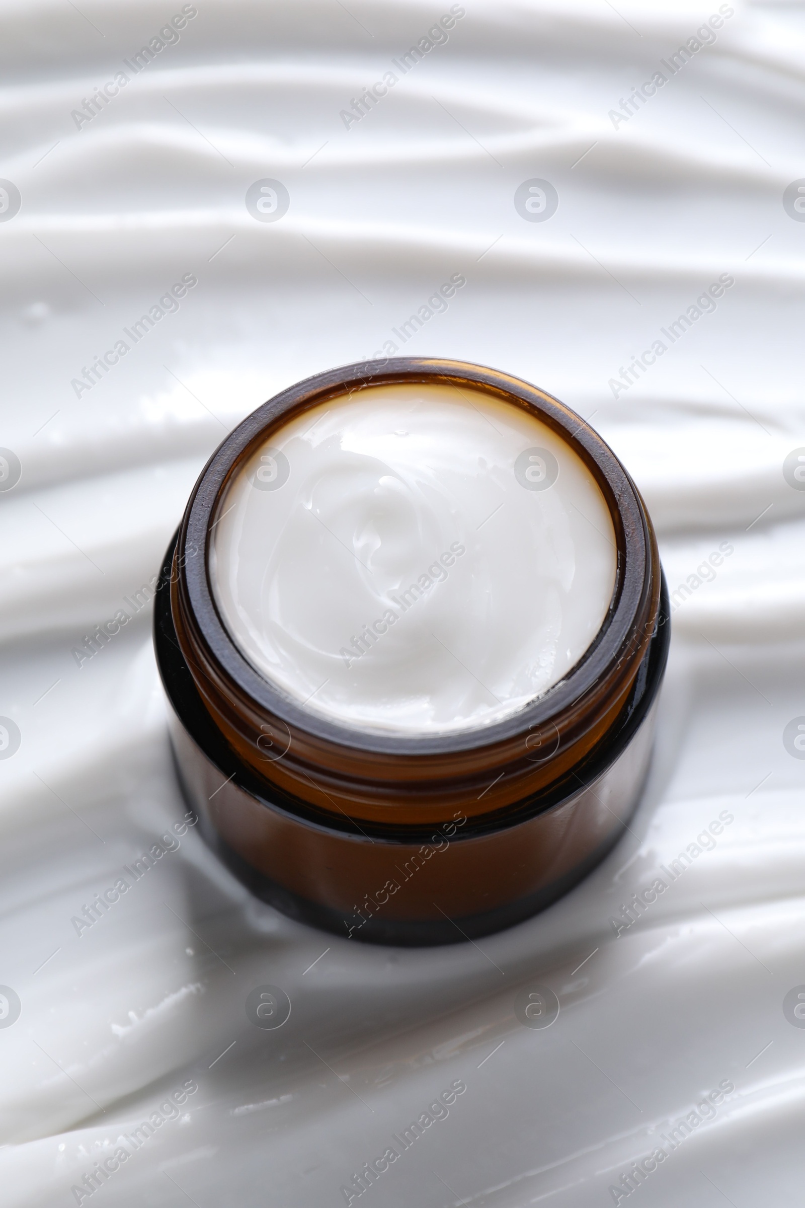 Photo of Face cream in jar on cosmetic product, closeup